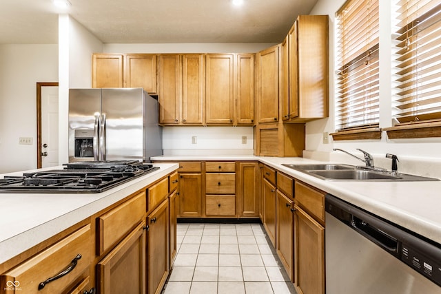 kitchen with a sink, appliances with stainless steel finishes, light tile patterned floors, and light countertops