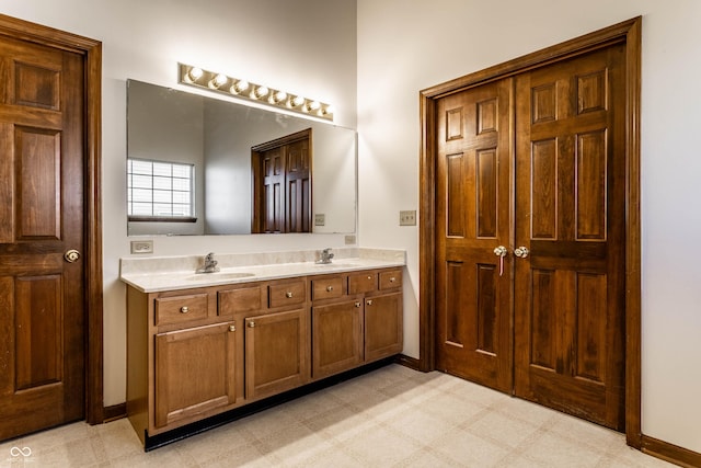 bathroom featuring a sink, baseboards, double vanity, and tile patterned floors