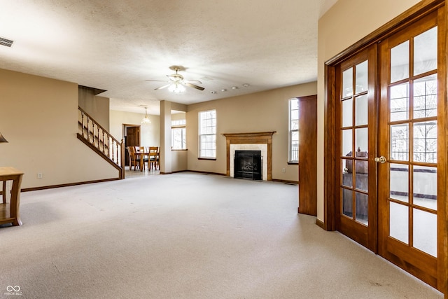 unfurnished living room with a textured ceiling, a tiled fireplace, baseboards, and light carpet