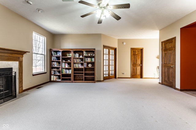 unfurnished living room with a tiled fireplace, baseboards, visible vents, and carpet floors