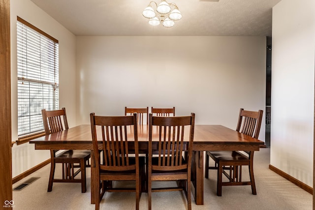 dining room featuring visible vents, baseboards, light colored carpet, and an inviting chandelier