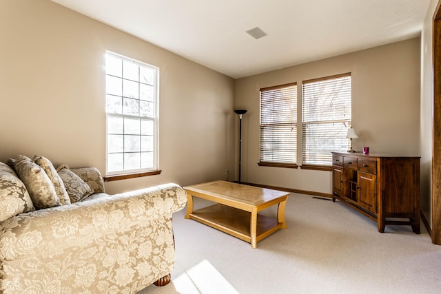 living room with baseboards, a healthy amount of sunlight, visible vents, and light carpet