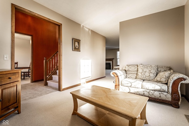 living room featuring stairway, a fireplace, baseboards, and light carpet