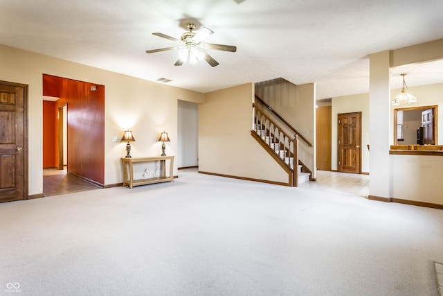 unfurnished living room with visible vents, stairway, carpet, baseboards, and ceiling fan