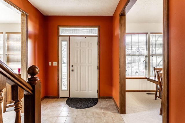 entrance foyer with light tile patterned floors, stairs, and baseboards