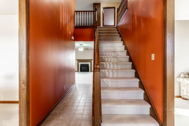 staircase with tile patterned flooring, a fireplace, and baseboards