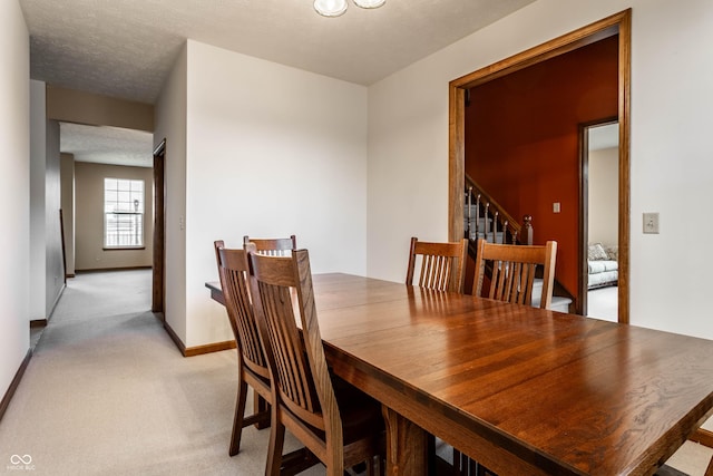 dining space with light carpet, stairway, a textured ceiling, and baseboards