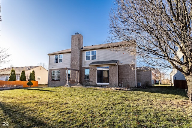 rear view of property with brick siding, fence, a lawn, and a chimney