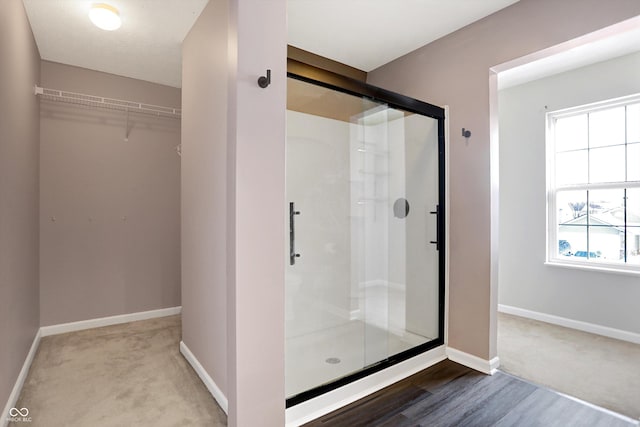 bathroom featuring a shower with shower door and wood-type flooring