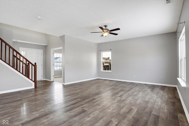 empty room with ceiling fan, a wealth of natural light, and dark hardwood / wood-style floors