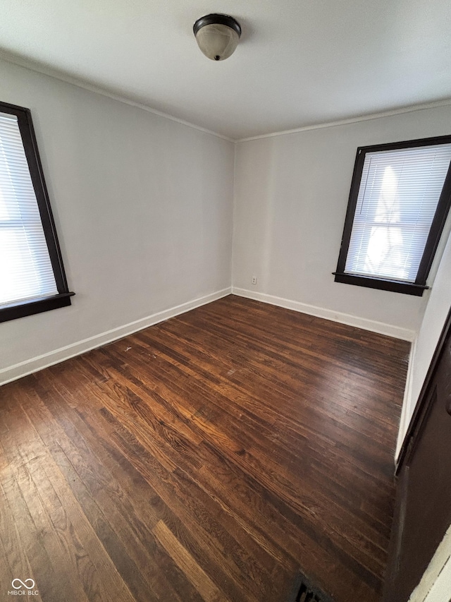 empty room with ornamental molding and dark wood-type flooring