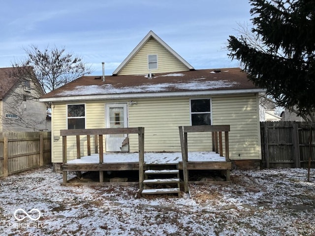 snow covered rear of property with a wooden deck