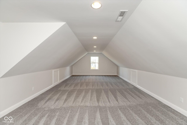 additional living space featuring light colored carpet and vaulted ceiling