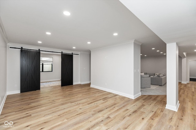 unfurnished living room featuring a barn door, light hardwood / wood-style flooring, and crown molding