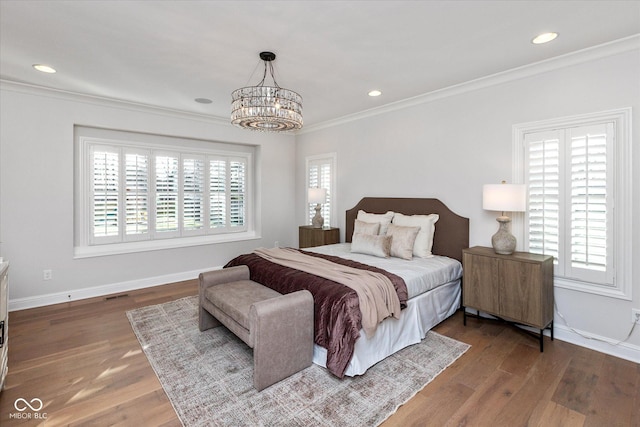 bedroom with hardwood / wood-style flooring, crown molding, multiple windows, and a notable chandelier