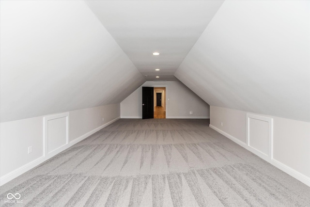 bonus room with light colored carpet and lofted ceiling