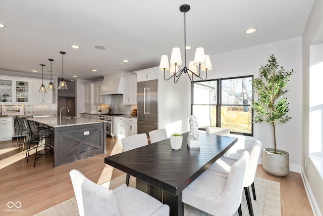 dining area featuring light hardwood / wood-style flooring, a notable chandelier, and sink