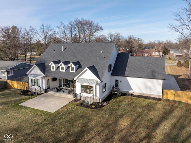 back of property with an outdoor living space, a patio, and a lawn