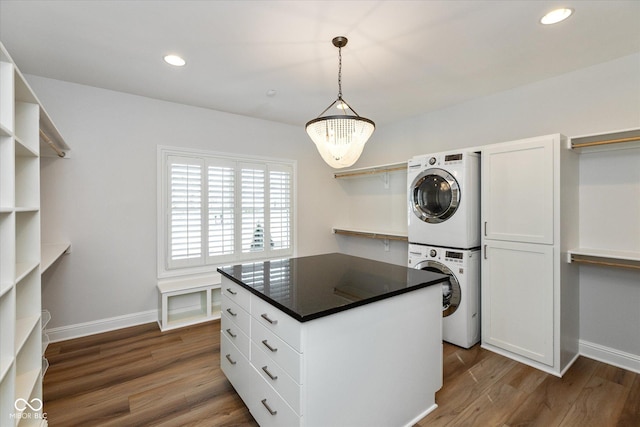 interior space with dark hardwood / wood-style flooring, stacked washing maching and dryer, and an inviting chandelier