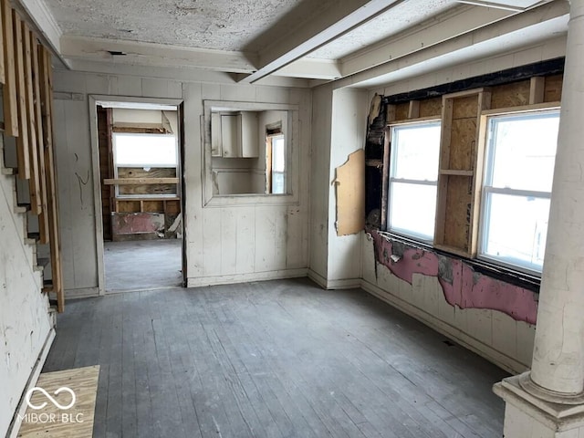 miscellaneous room with wood-type flooring, decorative columns, wood walls, and beam ceiling