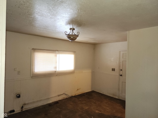 spare room with a textured ceiling and dark parquet floors