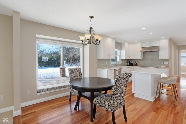 dining area with sink, plenty of natural light, a notable chandelier, and light wood-type flooring