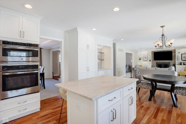 kitchen with white cabinetry, double oven, and a large fireplace