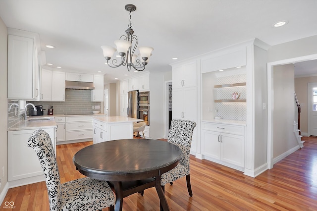 dining area with light wood-type flooring, a notable chandelier, and sink