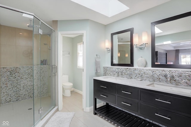 bathroom featuring a shower with shower door, backsplash, toilet, and a skylight