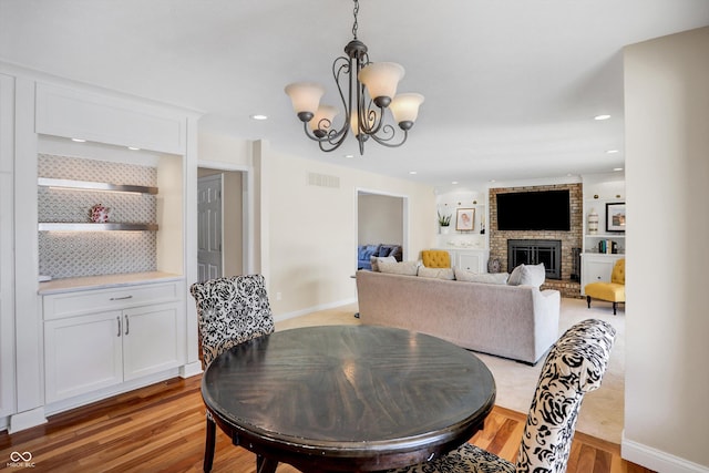 dining room featuring a fireplace, an inviting chandelier, and light hardwood / wood-style floors