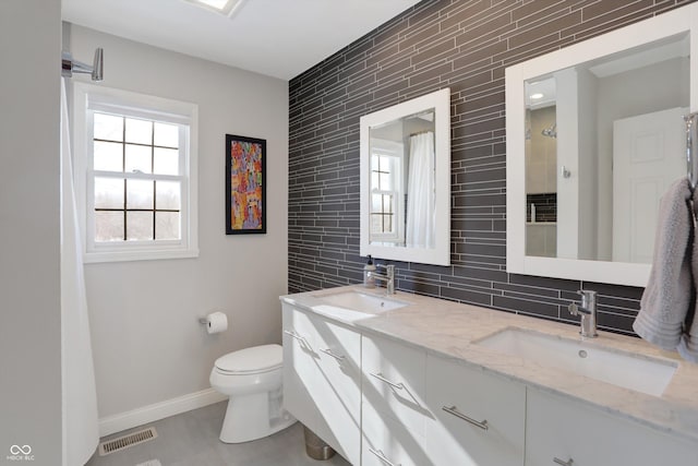 bathroom featuring toilet, vanity, and backsplash