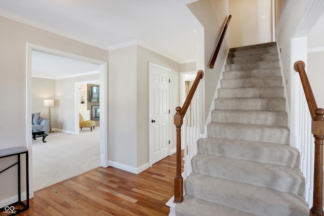 staircase with ornamental molding and hardwood / wood-style floors