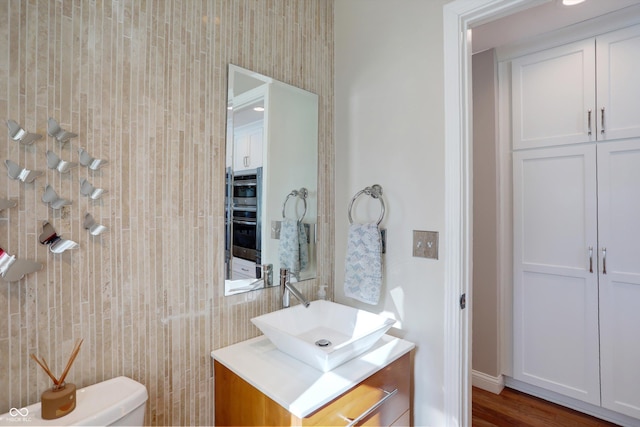 bathroom featuring toilet, vanity, and hardwood / wood-style floors