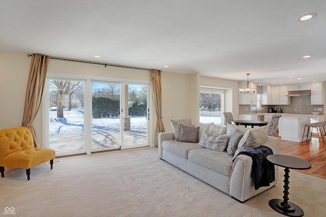 living room featuring plenty of natural light, sink, a chandelier, and light hardwood / wood-style flooring