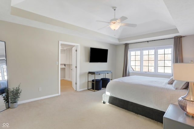 bedroom featuring ceiling fan, light carpet, and a tray ceiling