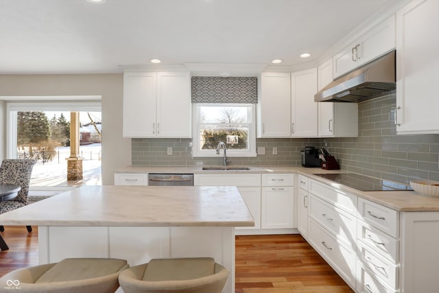 kitchen with white cabinetry, black electric stovetop, a breakfast bar area, stainless steel dishwasher, and sink