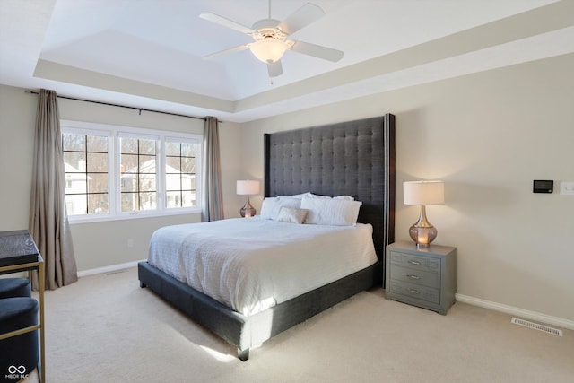 carpeted bedroom featuring ceiling fan and a raised ceiling