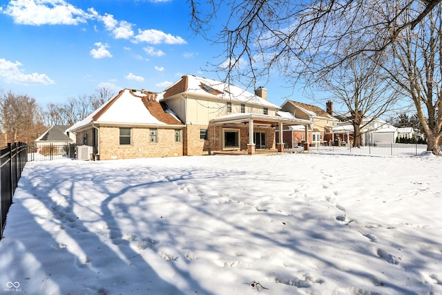 snow covered house featuring central AC unit