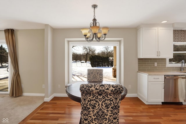 dining space with light wood-type flooring, a notable chandelier, and sink