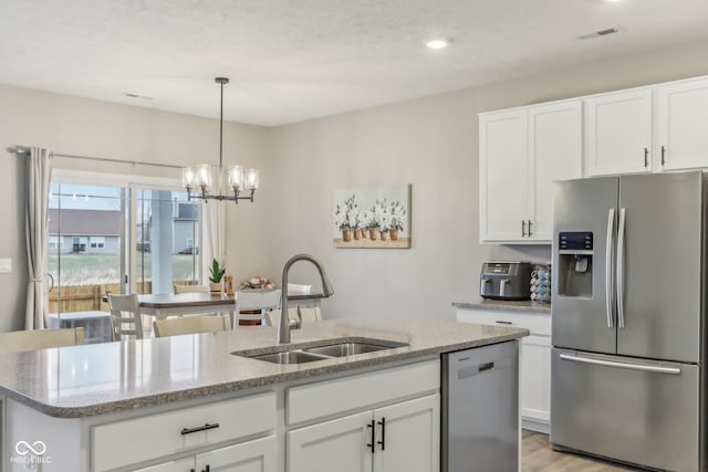 kitchen with white cabinetry, appliances with stainless steel finishes, a kitchen island with sink, and sink