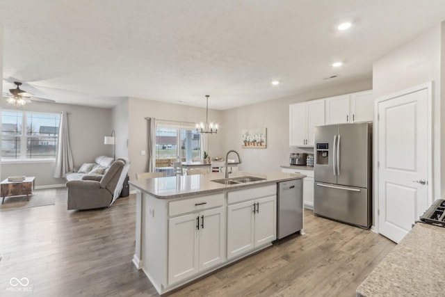 kitchen featuring appliances with stainless steel finishes, decorative light fixtures, sink, white cabinets, and light wood-type flooring