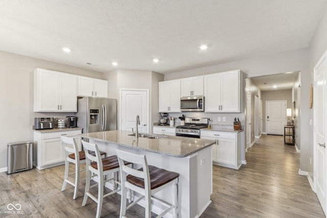 kitchen featuring an island with sink, appliances with stainless steel finishes, sink, and white cabinets