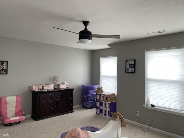 sitting room featuring light carpet, a textured ceiling, and ceiling fan