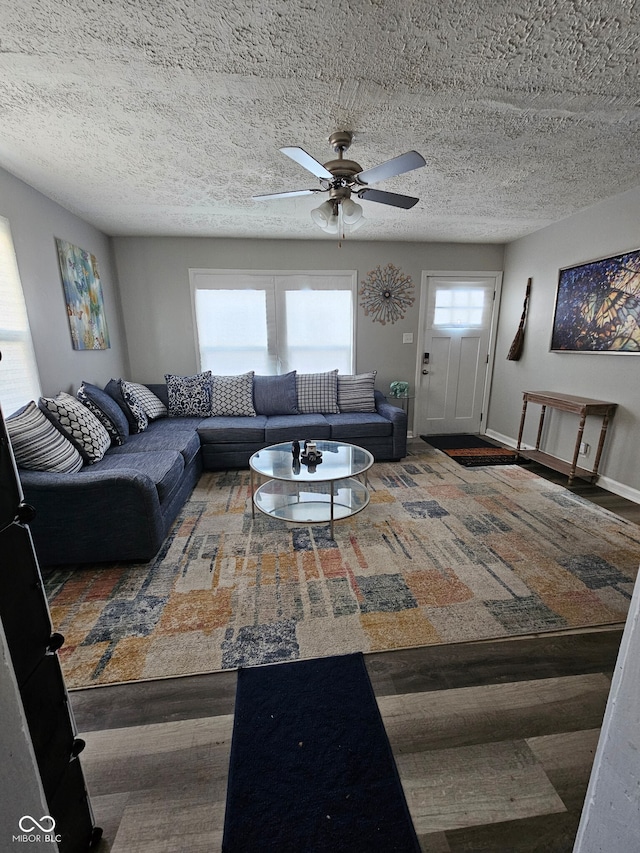 living room featuring ceiling fan, wood-type flooring, and a textured ceiling