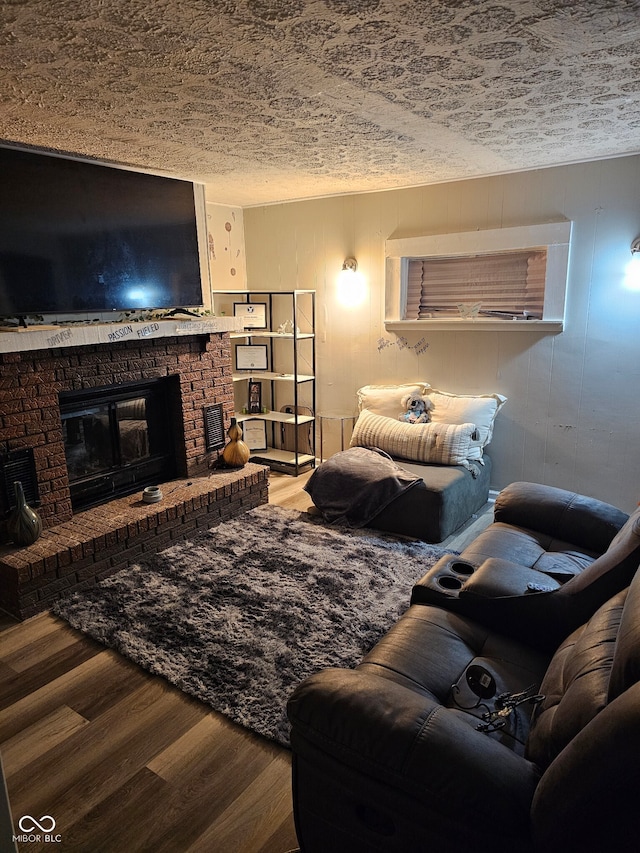 living room featuring hardwood / wood-style floors, a textured ceiling, and a brick fireplace