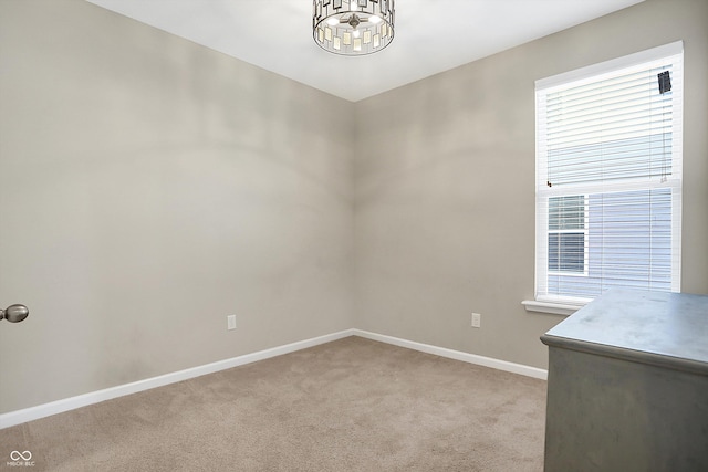 carpeted spare room featuring an inviting chandelier