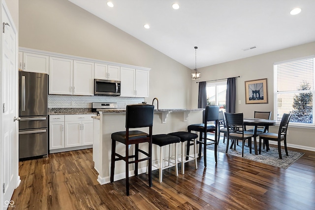 kitchen featuring a center island with sink, white cabinets, stone countertops, and appliances with stainless steel finishes