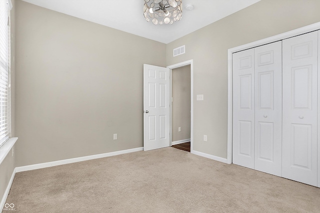 unfurnished bedroom with carpet, a chandelier, and a closet