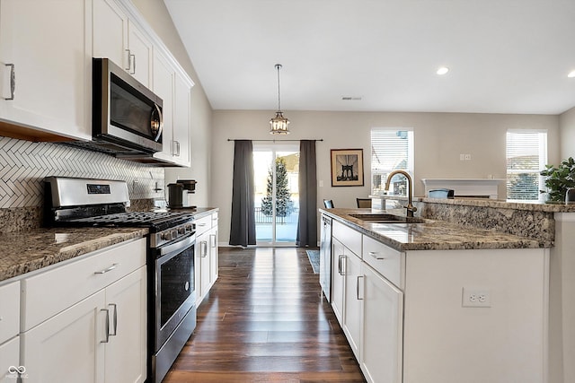 kitchen featuring a kitchen island with sink, sink, decorative light fixtures, white cabinetry, and stainless steel appliances