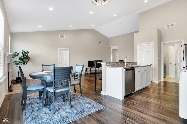 dining space with dark hardwood / wood-style floors, high vaulted ceiling, and sink